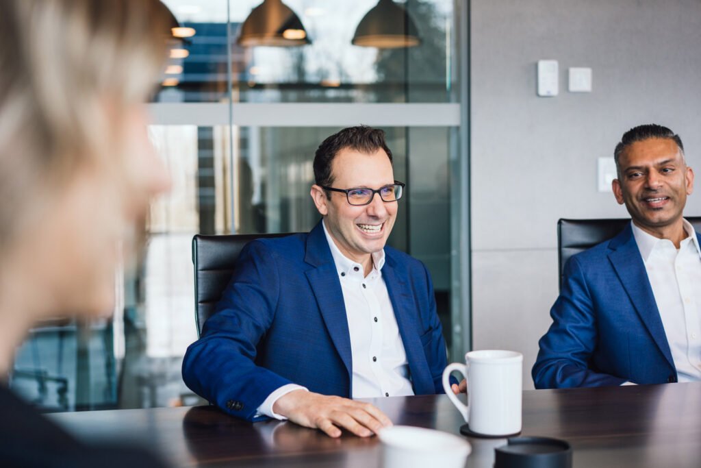 Two men sit at a board room table