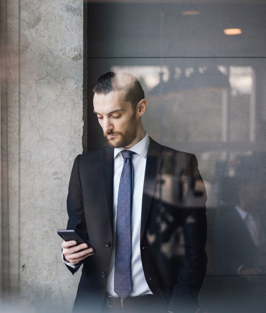 A business person on their phone standing in front of a window